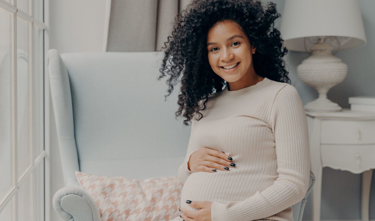 Beautiful pregnant african woman enjoying pregnancy, spending time at home